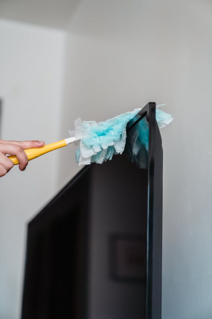 A picture of a person dusting a television screen